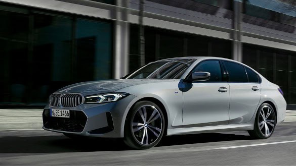 Silberner BMW 3er Limousine auf Straße vor einem modernen Gebäude.