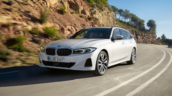 Weißer BMW 3er Touring fährt auf einer kurvigen Straße neben einer felsigen Landschaft.