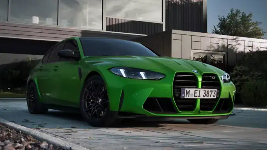 Grüner BMW 3er M Limousine auf Einfahrt vor modernem Gebäude.