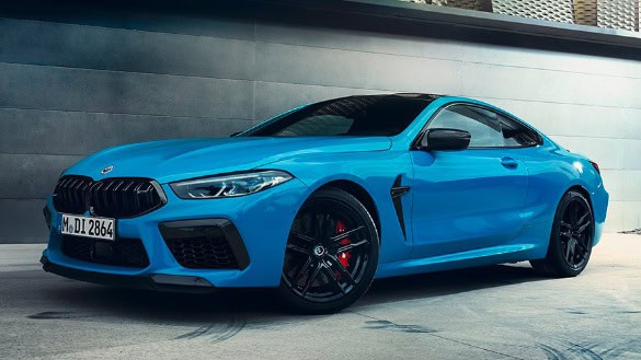 Blaues BMW Coupé steht seitlich auf einer Straße vor einer grauen Wand.