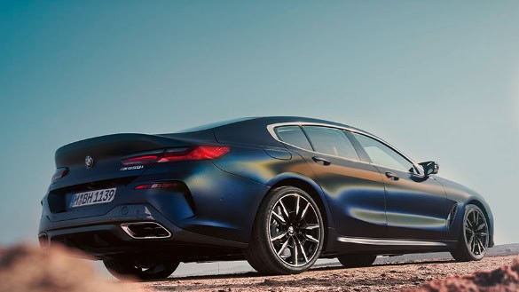 Blaues BMW 8er Gran Coupé von hinten auf einer Straße bei klarem Himmel.