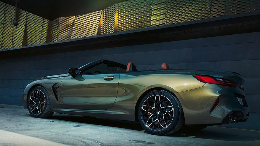 BMW 8er Cabrio in Grün, seitliche Ansicht, geparkt vor moderner Fassade.