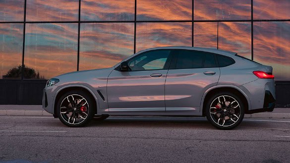 Roter BMW SUV fährt auf einer Straße unter einer Brücke bei Tageslicht.