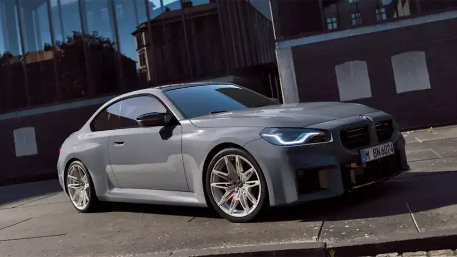 Graues BMW Coupé auf Straße vor modernem Gebäude bei Tageslicht, seitliche Ansicht.