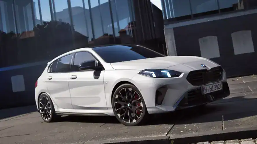 Weißer BMW M-Modell vor moderner Glasfassade, seitliche Ansicht, tagsüber.