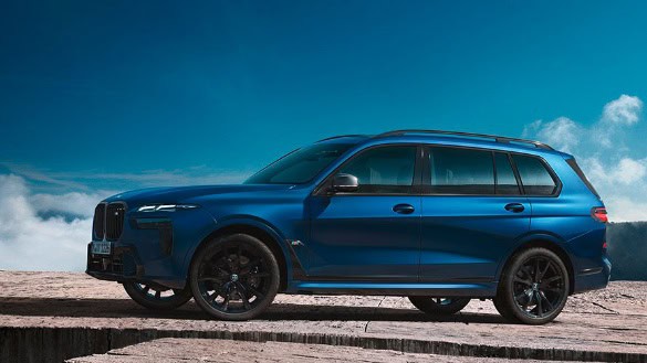 Blauer BMW X7 SUV in Seitenansicht vor blauem Himmel, auf einem steinigen Untergrund.