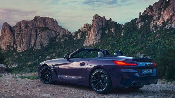 Lila BMW Z4 Roadster vor Felslandschaft bei Sonnenuntergang.