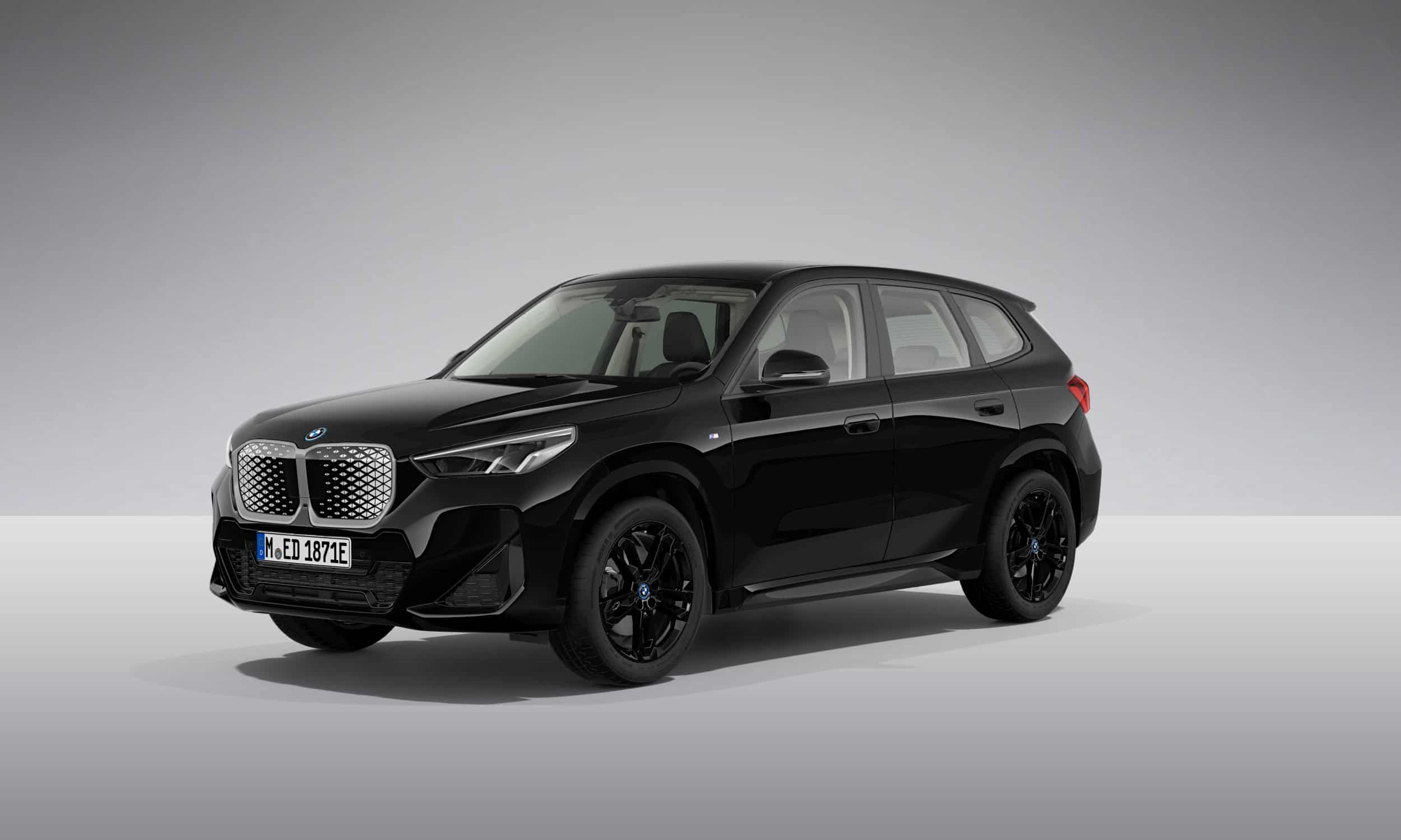 Schwarzer BMW iX1 SUV auf grauem Hintergrund, Seitenansicht von vorne links.